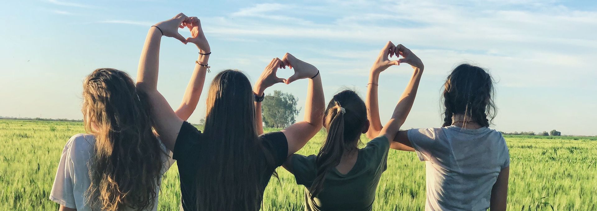 Vier junge Frauen formen Herzen mit ihren Händen