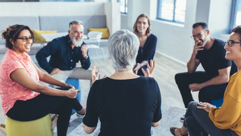 Menschen sitzen in einem Sitzkreis Team sitzt im Stuhlkreis und diskutiert
