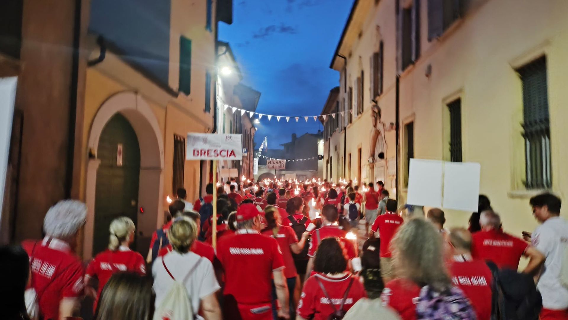 Es ist dunkel. Eine größe Menge Menschen läuft friedlich mit Fackeln durch eine Stadt. 